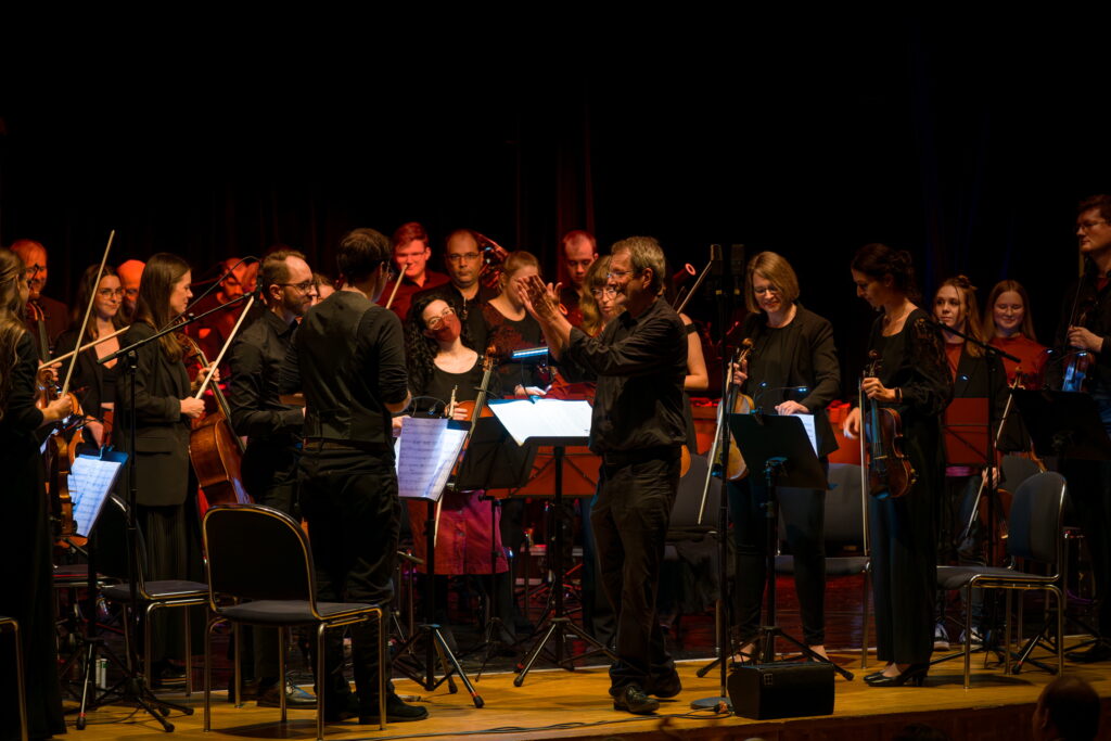 Nach dem Konzert steht das Orchester auf um den Applaus in Empfang zu nehmen