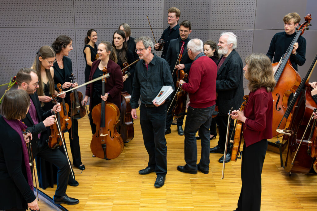 Die Musiker des Neuen Burgthanner Streichensembles stehen im Probenraum und unterhalten sich angeregt