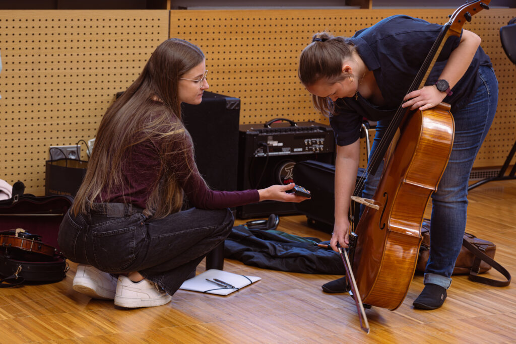 Eine junge Musikerin des Neuen Burgthanner Streichensembles hilft der ersten Cellistin beim Einstimmen ihres Instruments