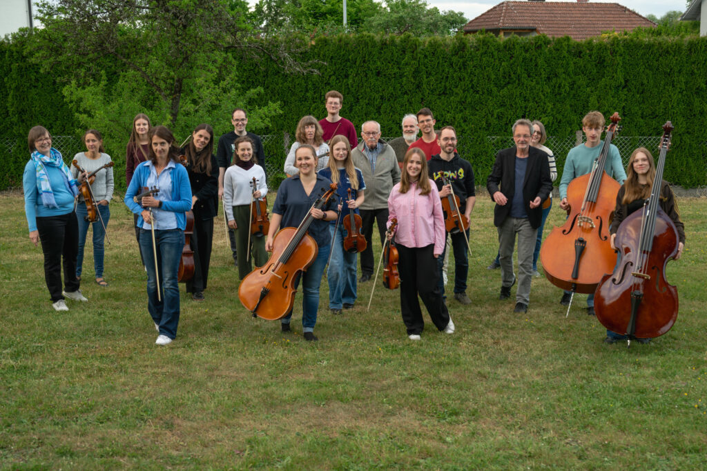 Das Neue Burgthanner Streichensemble läuft locker mit den Instrumenten über den Rasen auf die Kamera zu 